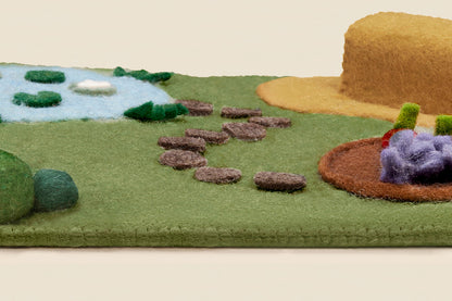 Edge view of the farm play mat showing wool felt thickness and blanket stitching