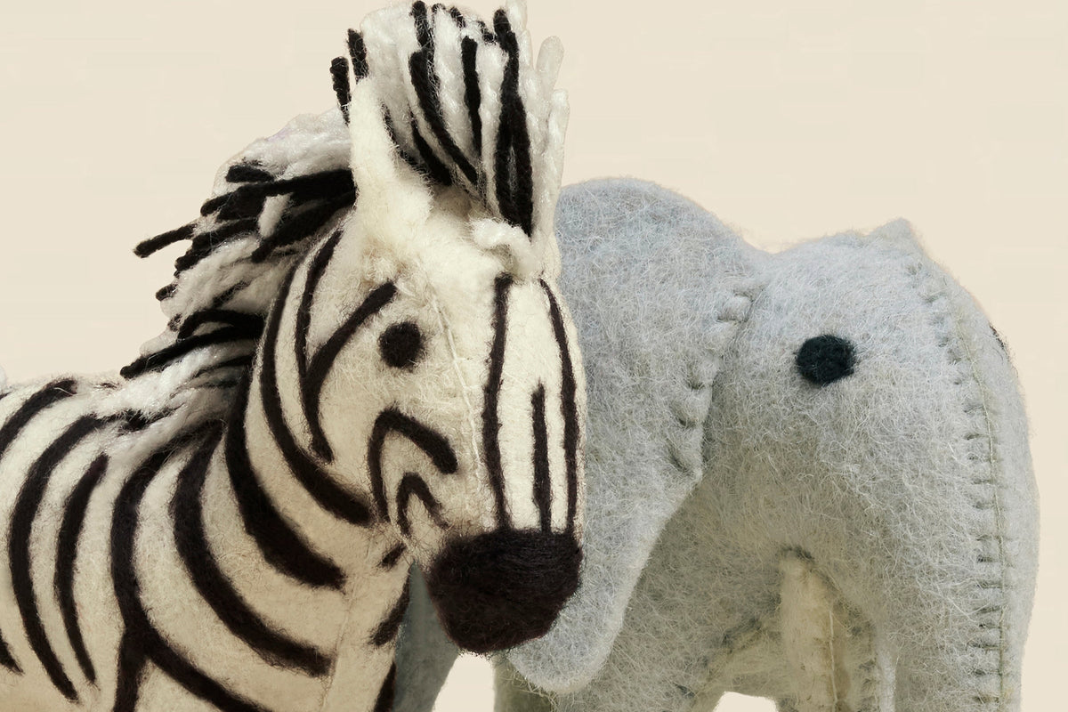 Close-up of hand stitching on a wool felt zebra and elephant